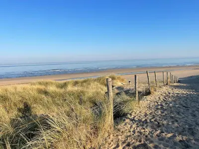 a fence on a sandy beach near the ocean at Wendy's Tiny Beachhouse in Noordwijk