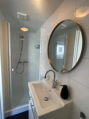 a bathroom with a sink and a shower with a mirror at Wendy's Tiny Beachhouse in Noordwijk