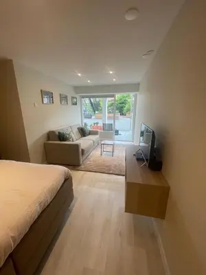 a bedroom with a bed and a couch and a tv at Studio Alexander with private indoor parking in Zandvoort