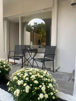 a patio with two chairs and a table and flowers at Studio Alexander with private indoor parking in Zandvoort