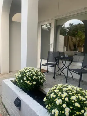a porch with two chairs and a table and flowers at Studio Alexander with private indoor parking in Zandvoort