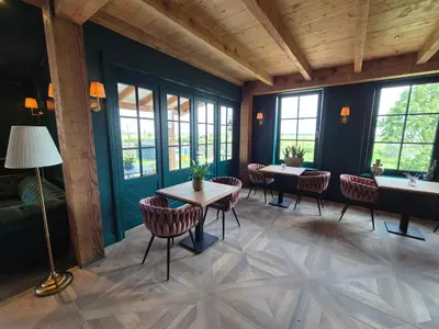 a room with a table and chairs and windows at Bed and Breakfast Zomerzicht in Oudendijk