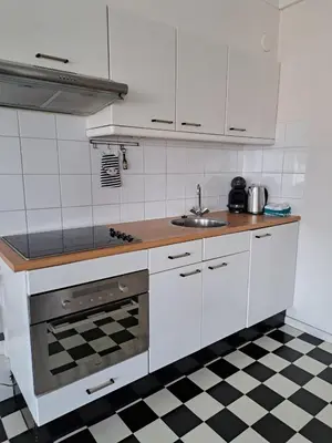 a kitchen with white appliances and a checkered floor at Chang in Egmond aan den Hoef