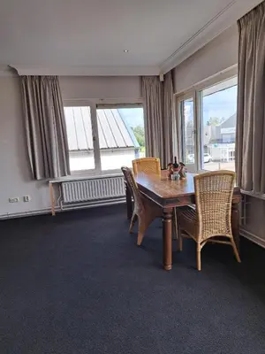 a dining room with a table and chairs and windows at Chang in Egmond aan den Hoef