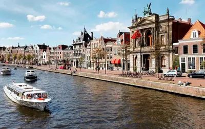 a boat in a river in a city with buildings at B&B De Amsterdamse Poort in Haarlem