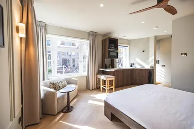 a bedroom with a bed and a chair and a kitchen at Boutique Studio VO38 in Alkmaar