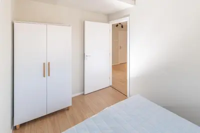 an empty bedroom with white cabinets and a bed at B&b aan zee in Egmond aan Zee