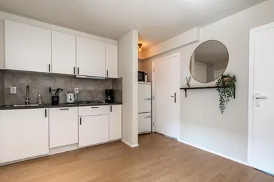 a kitchen with white cabinets and a mirror at B&b aan zee in Egmond aan Zee