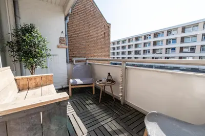 a balcony with a chair and a table and a building at B&b aan zee in Egmond aan Zee
