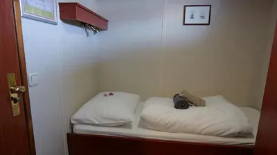 a small bed with white sheets and a stuffed animal on it at Botel Clair d'Etoile in Amsterdam