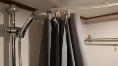 a shower head in a bathroom with black curtains at Botel Clair d'Etoile in Amsterdam