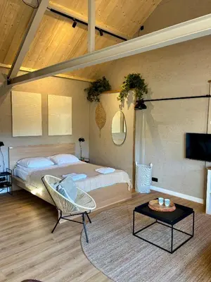 a bedroom with a bed and a chair and a tv at Saltéa Beach House Noordwijk in Noordwijk aan Zee