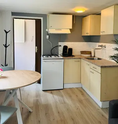 a kitchen with white appliances and a table at Het zandhuisje 84 in Noordwijk aan Zee