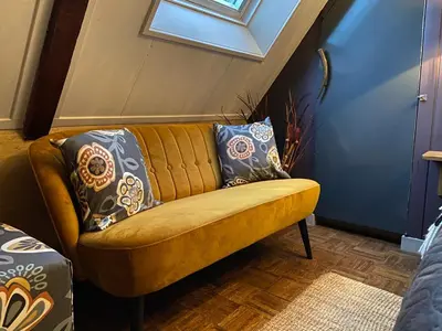 a yellow couch with pillows on it in a room at Agapanthus bed and breakfast in Hoogkarspel