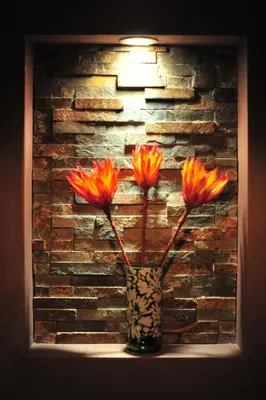 a vase with flowers in front of a brick wall at Agapanthus bed and breakfast in Hoogkarspel