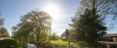a house and trees with the sun in the sky at NEW! Nightglow Residency in Oosteinde