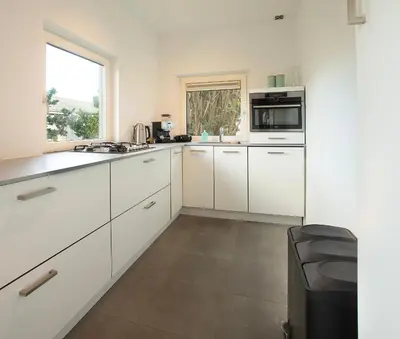 a kitchen with white cabinets and a window at NEW! Nightglow Residency in Oosteinde