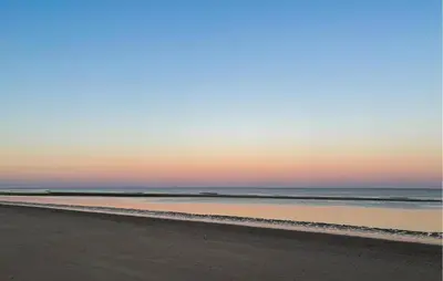 a beach at sunset with the ocean in the background at Nice Apartment In Bergen Aan Zee in Bergen aan Zee