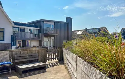 a house with a wooden fence and a bench at Nice Apartment In Bergen Aan Zee in Bergen aan Zee