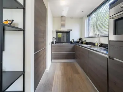 a kitchen with wooden cabinets and a large window at Villa in Egmond near Beach & Windmill in Egmond aan den Hoef