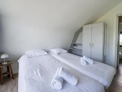 a bedroom with a large white bed with towels on it at Villa in Egmond near Beach & Windmill in Egmond aan den Hoef