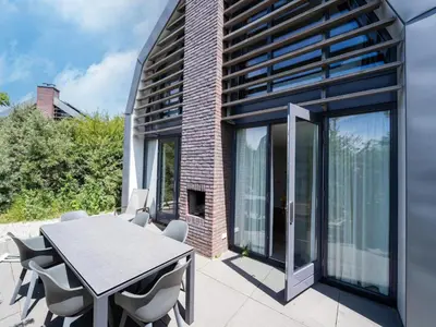 a dining room with a table and chairs on a patio at Villa in Egmond near Beach & Windmill in Egmond aan den Hoef