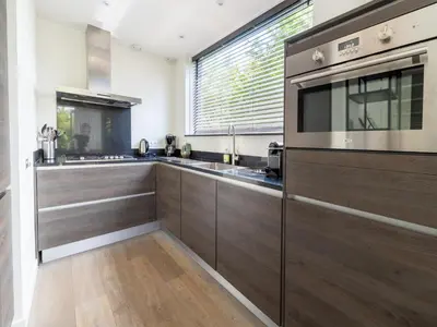 a kitchen with wooden cabinets and a large window at Villa in Egmond near Beach & Windmill in Egmond aan den Hoef