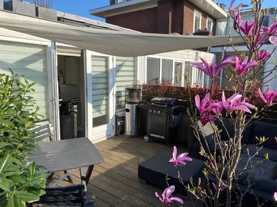 a patio with a grill and purple flowers on a deck at Rooftop Terrace Apartment in Amsterdam