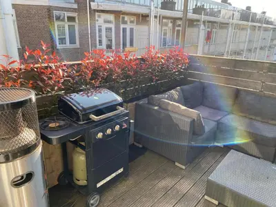 a grill and a couch on a balcony at Rooftop Terrace Apartment in Amsterdam