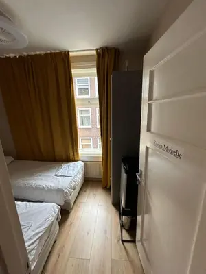 a small room with two beds and a window at michelle in Amsterdam