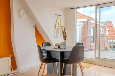 a dining room with a table and chairs and a window at Stay de Laat in Alkmaar