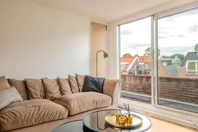 a living room with a couch and a large window at Stay de Laat in Alkmaar