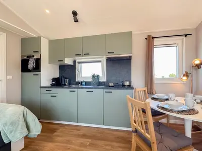 a kitchen with green cabinets and a table and a dining room at Fuut 24-28 in Breukelen