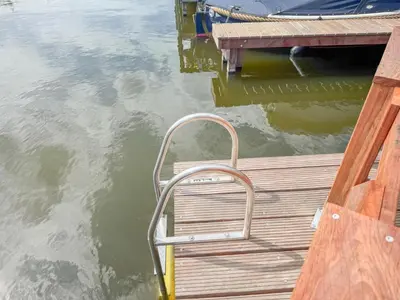 a wooden dock with a metal chair on the water at Fuut 24-26 in Breukelen