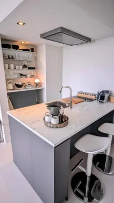 a kitchen with a counter with a sink and stools at Studio Lumare-Inn in Bergen aan Zee