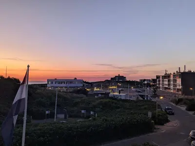 a view of a city at sunset with a flag at Studio Lumare-Inn in Bergen aan Zee