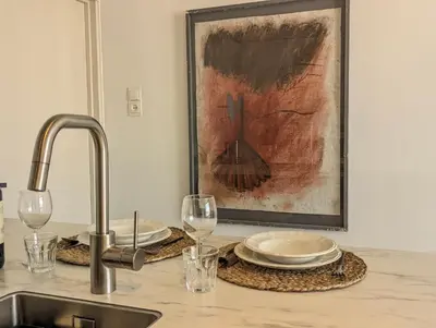 a kitchen counter with a sink and glasses and a painting at Studio Lumare-Inn in Bergen aan Zee