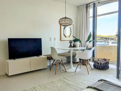 a living room with a tv and a table and chairs at Studio Lumare-Inn in Bergen aan Zee