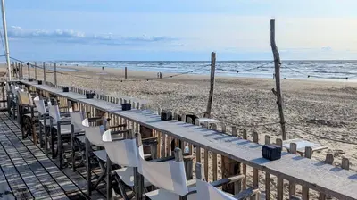 a row of chairs on a boardwalk on the beach at Studio Lumare-Inn in Bergen aan Zee