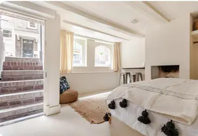 a white bedroom with a bed and a window at Luxury canal suite in the best location of Amsterdam !!! in Amsterdam