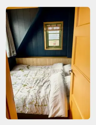 a bed in a blue room with a window at House next to Amsterdam in Landsmeer