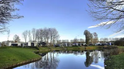 a view of a river with houses in the background at Holiday home - area AMSTERDAM - 6 people in Halfweg