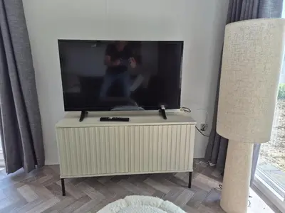 a flat screen tv on a stand in a living room at Chalet 549 op Recreatiepark de Wielen in Sint Maarten