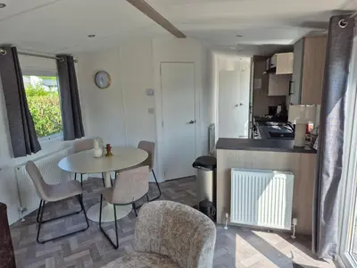 a kitchen and dining room with a table and chairs at Chalet 549 op Recreatiepark de Wielen in Sint Maarten