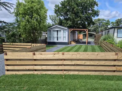 a backyard with a wooden fence and a house at Chalet 549 op Recreatiepark de Wielen in Sint Maarten