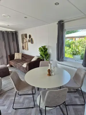 a living room with a white table and chairs at Chalet 549 op Recreatiepark de Wielen in Sint Maarten