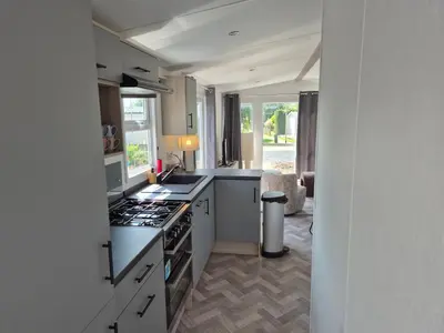 a kitchen with white cabinets and a stove top oven at Chalet 549 op Recreatiepark de Wielen in Sint Maarten