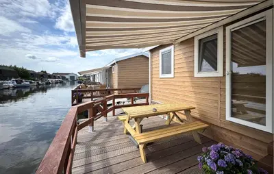 a wooden deck with benches and tables next to the water at Nice Home In Breukelen in Breukelen