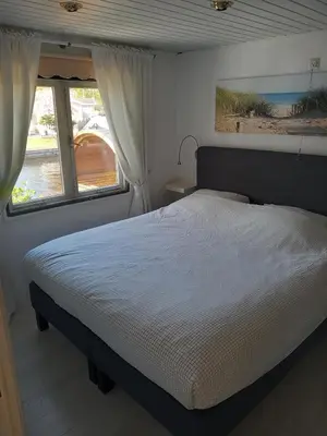 a bedroom with a large bed and a window at Chalet with waterfront sauna and boat in Loosdrecht