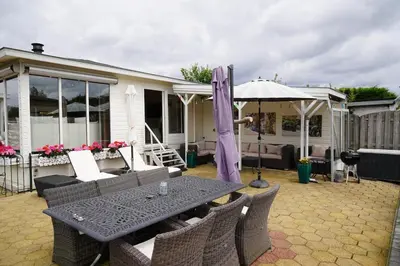 a patio with a table and chairs and an umbrella at Chalet with waterfront sauna and boat in Loosdrecht